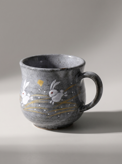 Gray ceramic mug with rabbit illustrations on a neutral background