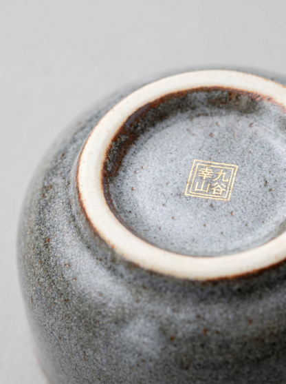 Close-up of a ceramic cup with a gold stamp on a gray background