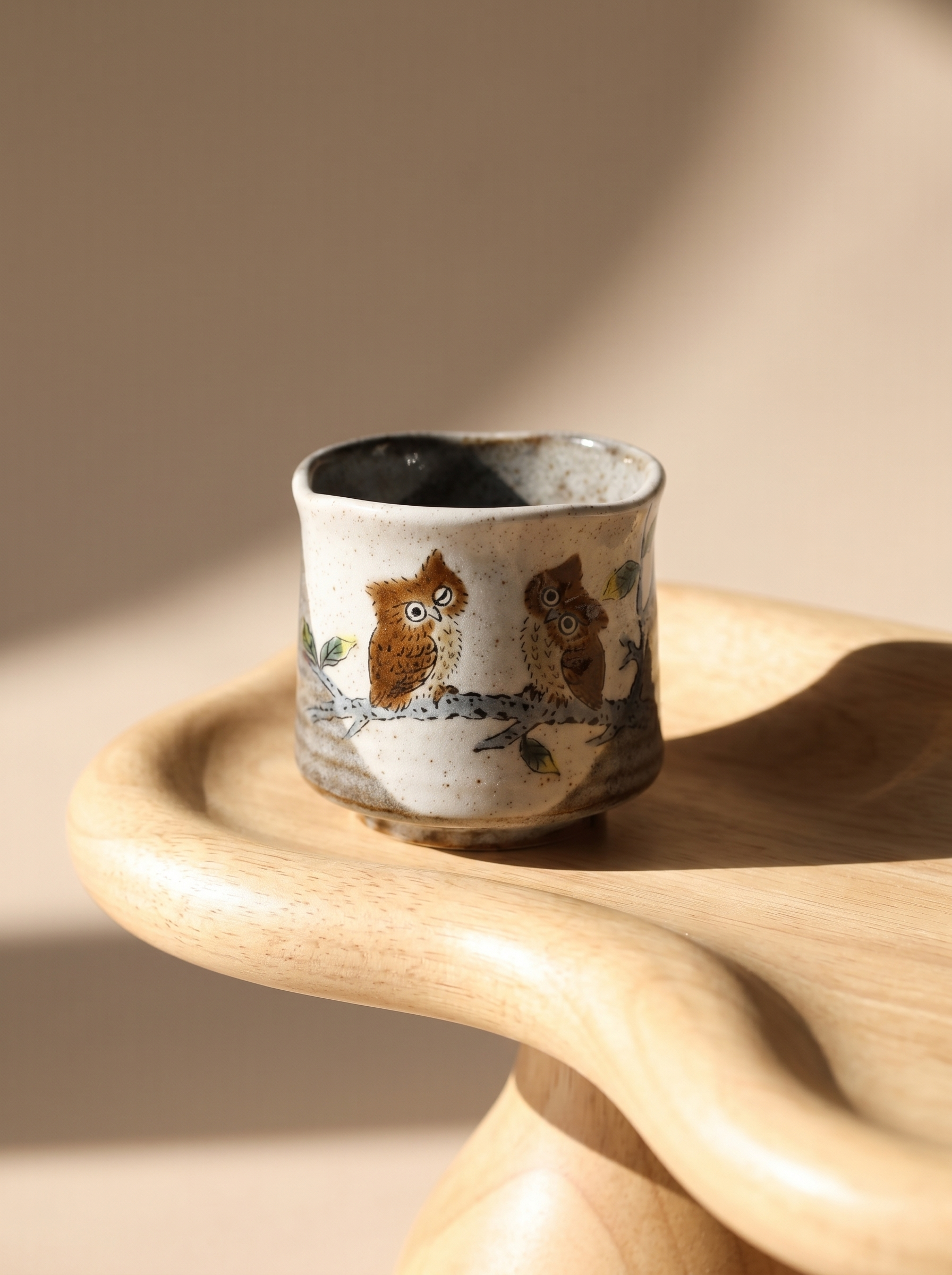 Ceramic cup with owl design on a wooden surface