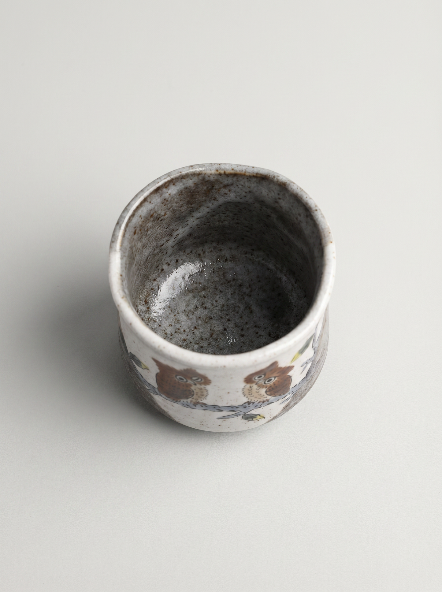 Ceramic cup with owl design on a light gray background top view