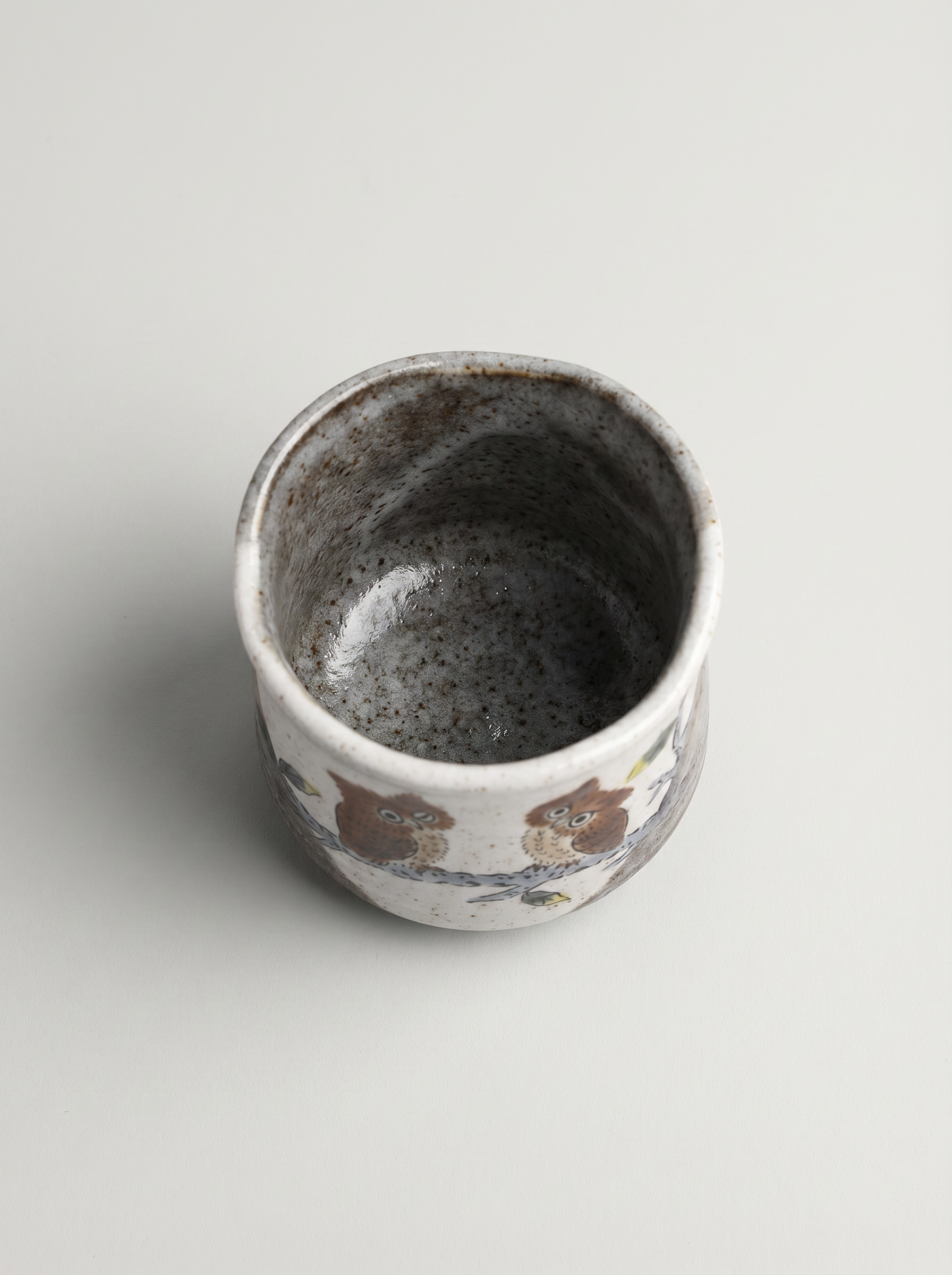 Ceramic cup with owl design on a light gray background top view