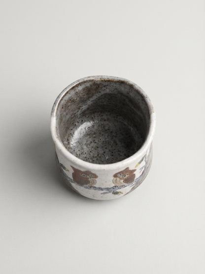 Ceramic cup with owl design on a light gray background top view