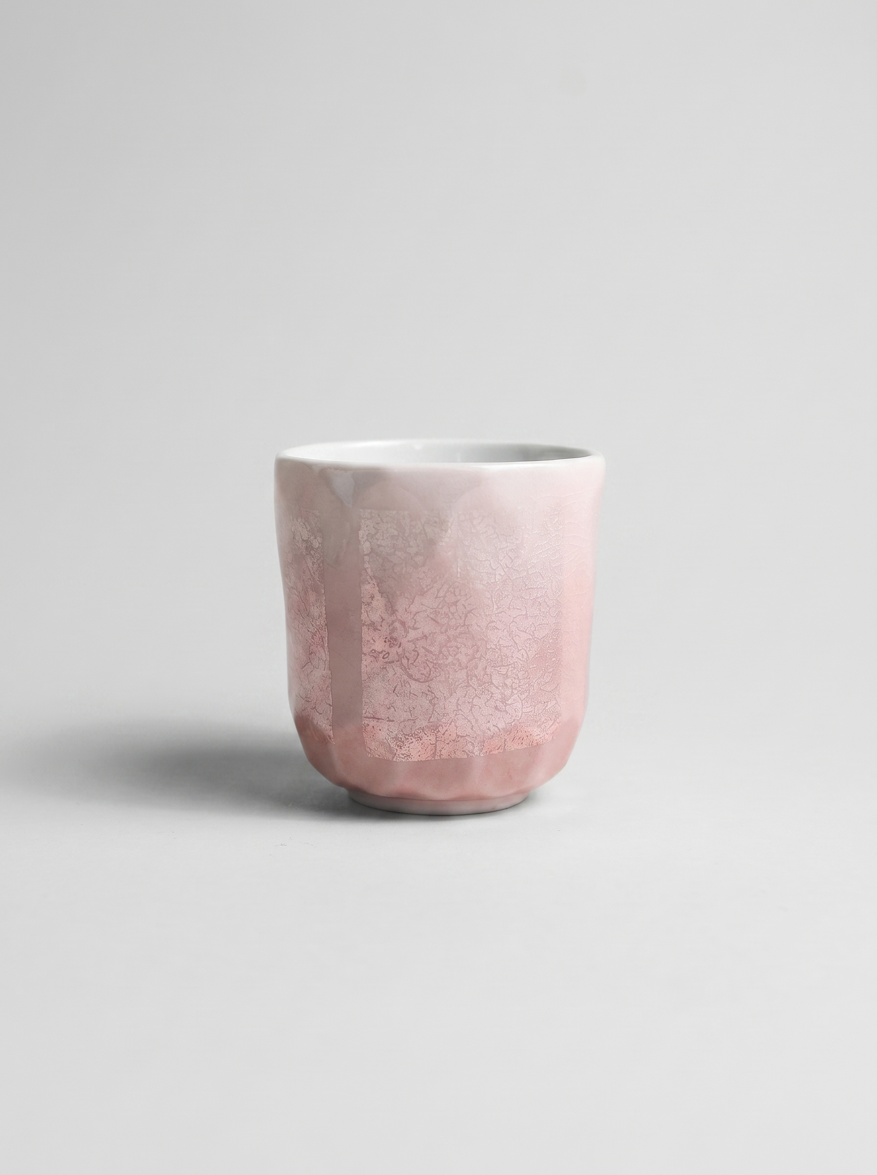 Japanese pink ceramic cup with ginsai finish on a light gray background