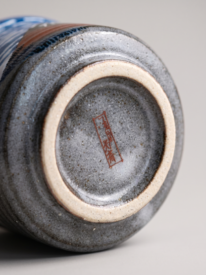 Close-up of a ceramic cup with a visible brand logo on a gray background