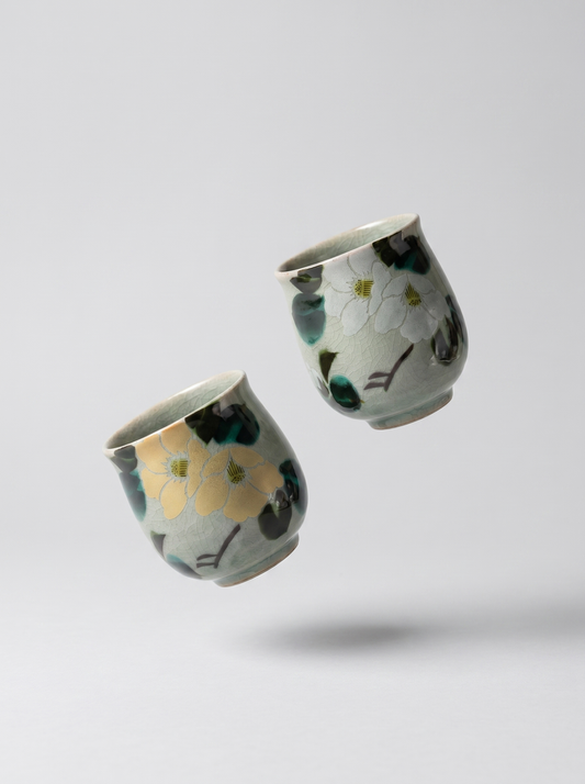 Two ceramic cups with floral patterns on a light gray background