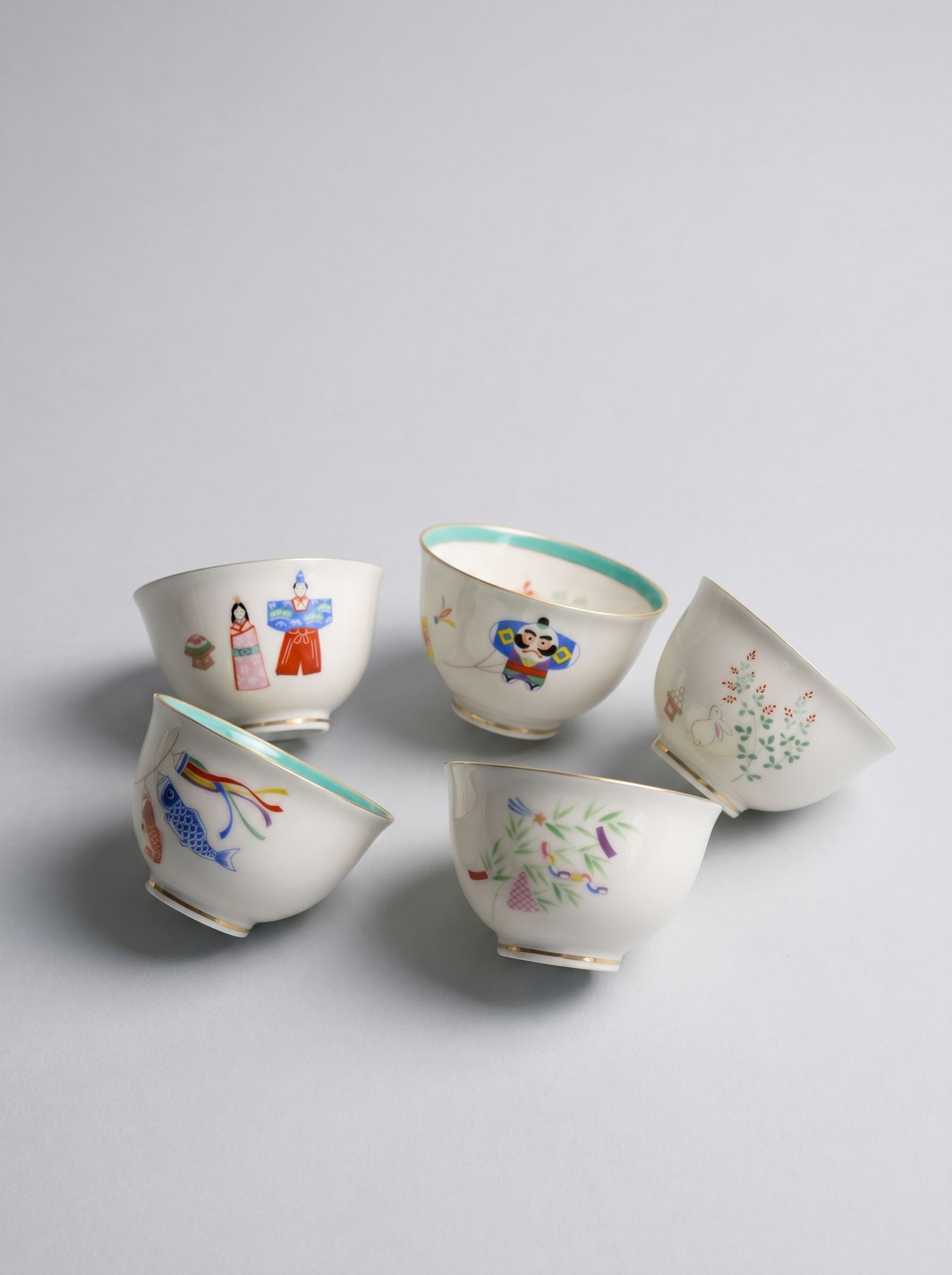 Five ceramic cups with colorful illustrations on a light gray background