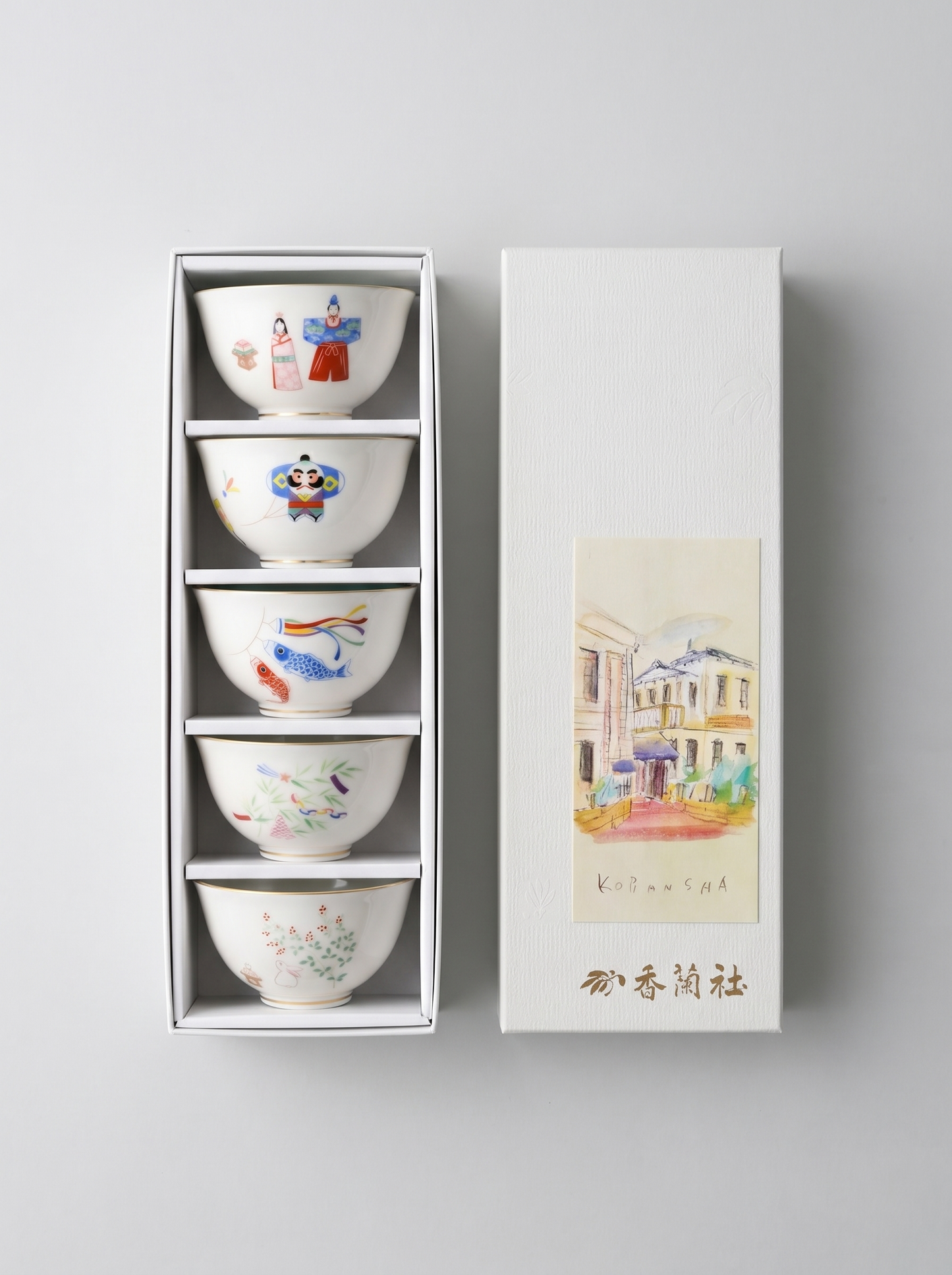 Set of five small Japanese porcelain bowls with colorful designs in a white gift box on a light gray background