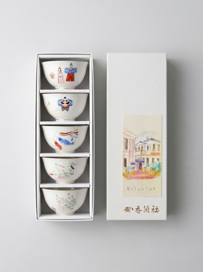 Set of five small Japanese porcelain bowls with colorful designs in a white gift box on a light gray background
