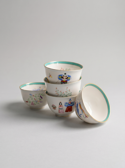 Set of five porcelain teacups with colorful illustrations on a gray background