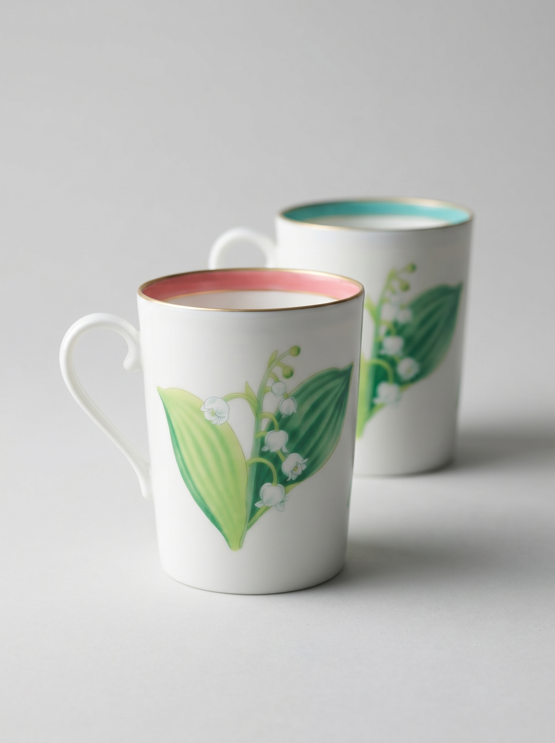 Japanese koransha porcelain set of 2 teacups with short handles and a lily of the valley design in turquoise and coral colors, blurred background