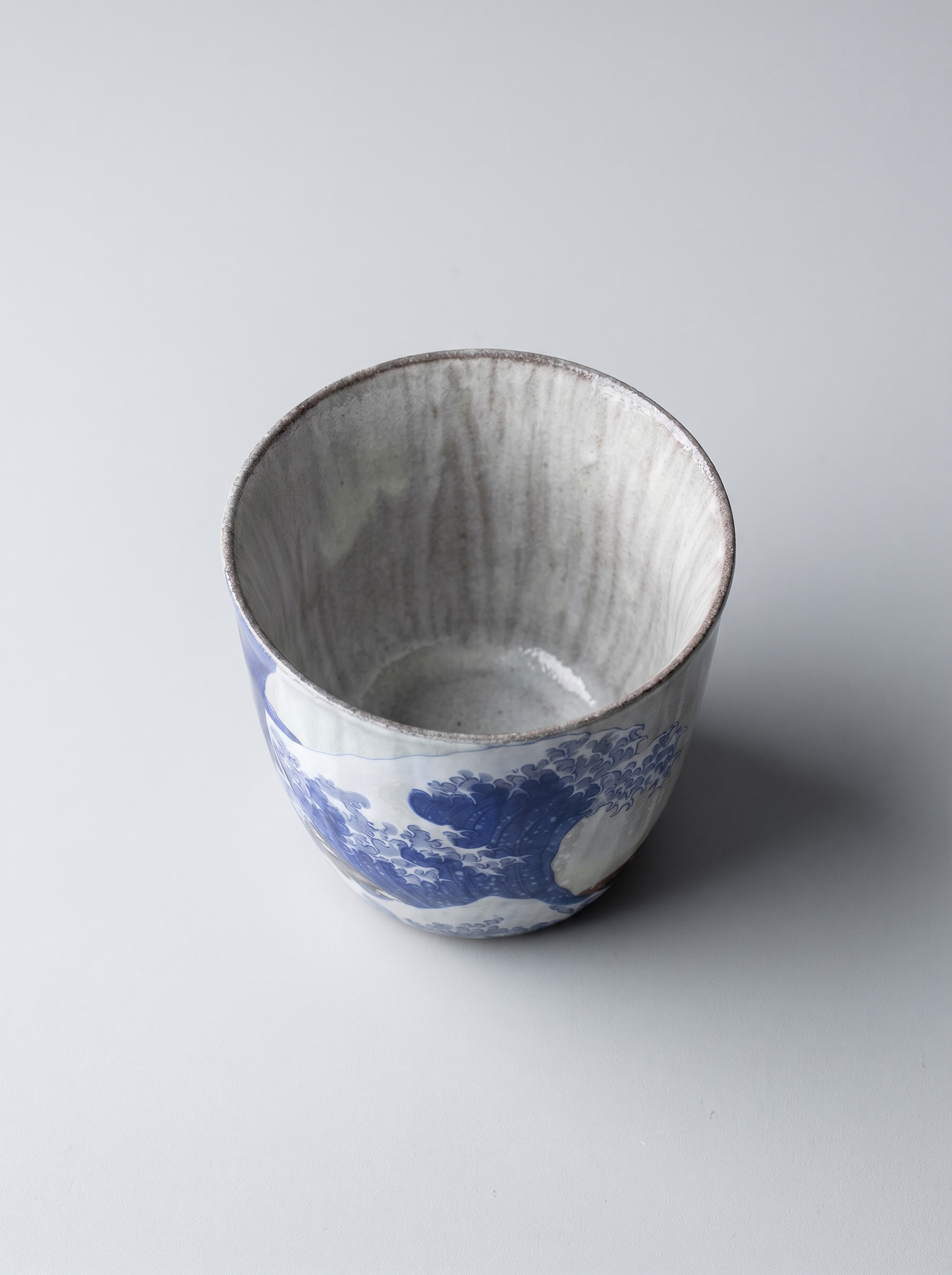 Japanese kutani ceramic teacup with The Great Wave off Kanagawa design with no handle on a grey background top view