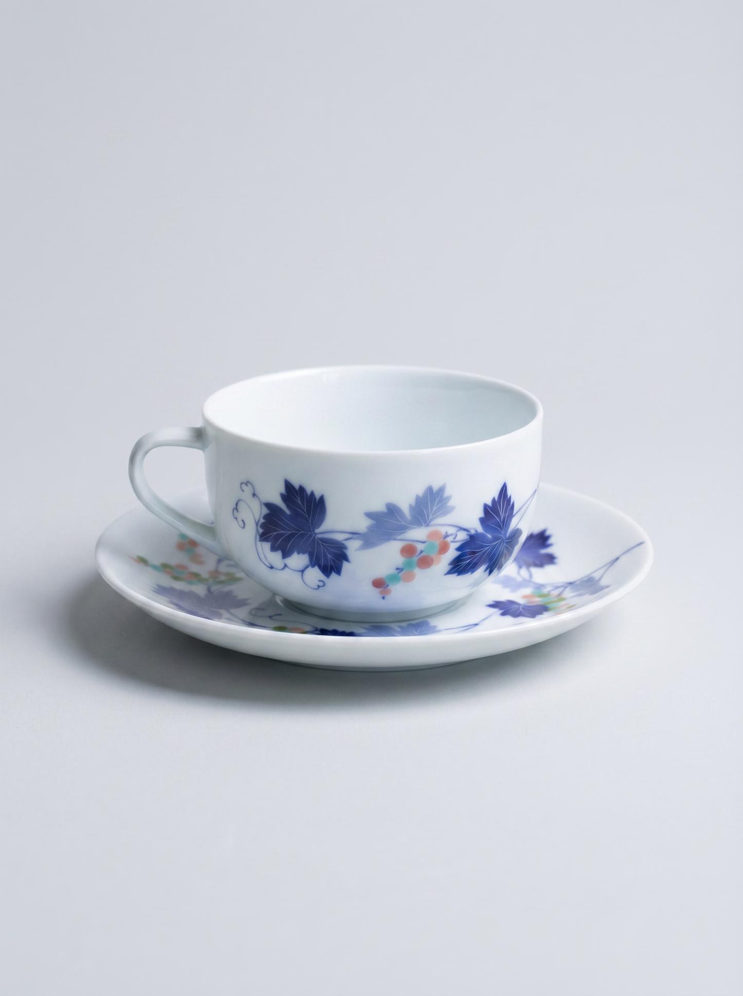 Ceramic cup and saucer with floral design on a light gray background front facing