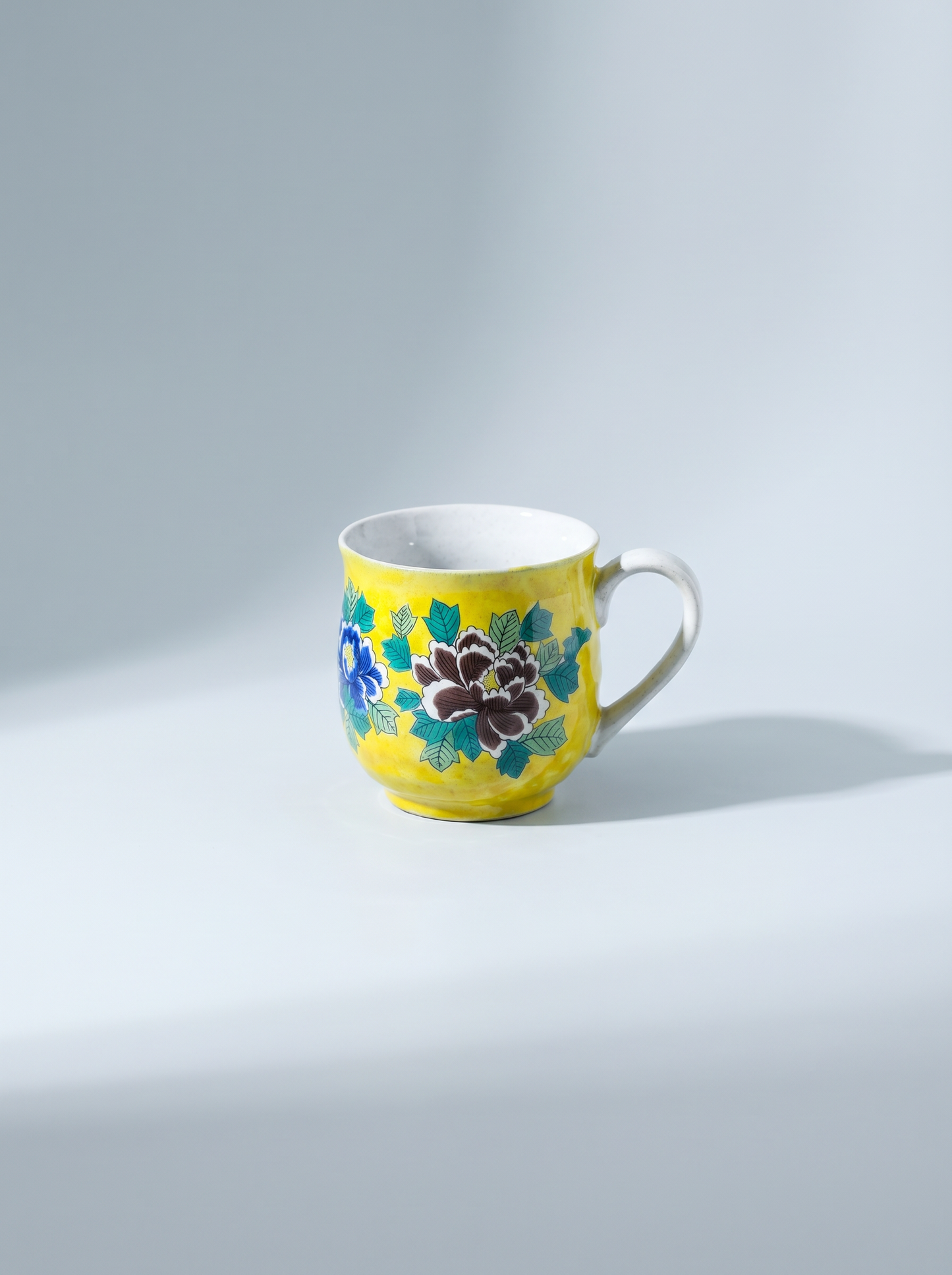 Yellow mug with floral design on a light gray background