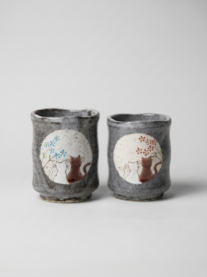 Set of two Japanese ceramic teacups with no handle with a cats in sunny spot yunomi design on a grey background