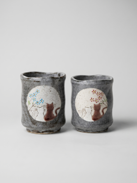 Set of two Japanese ceramic teacups with no handle with a cats in sunny spot yunomi design on a grey background
