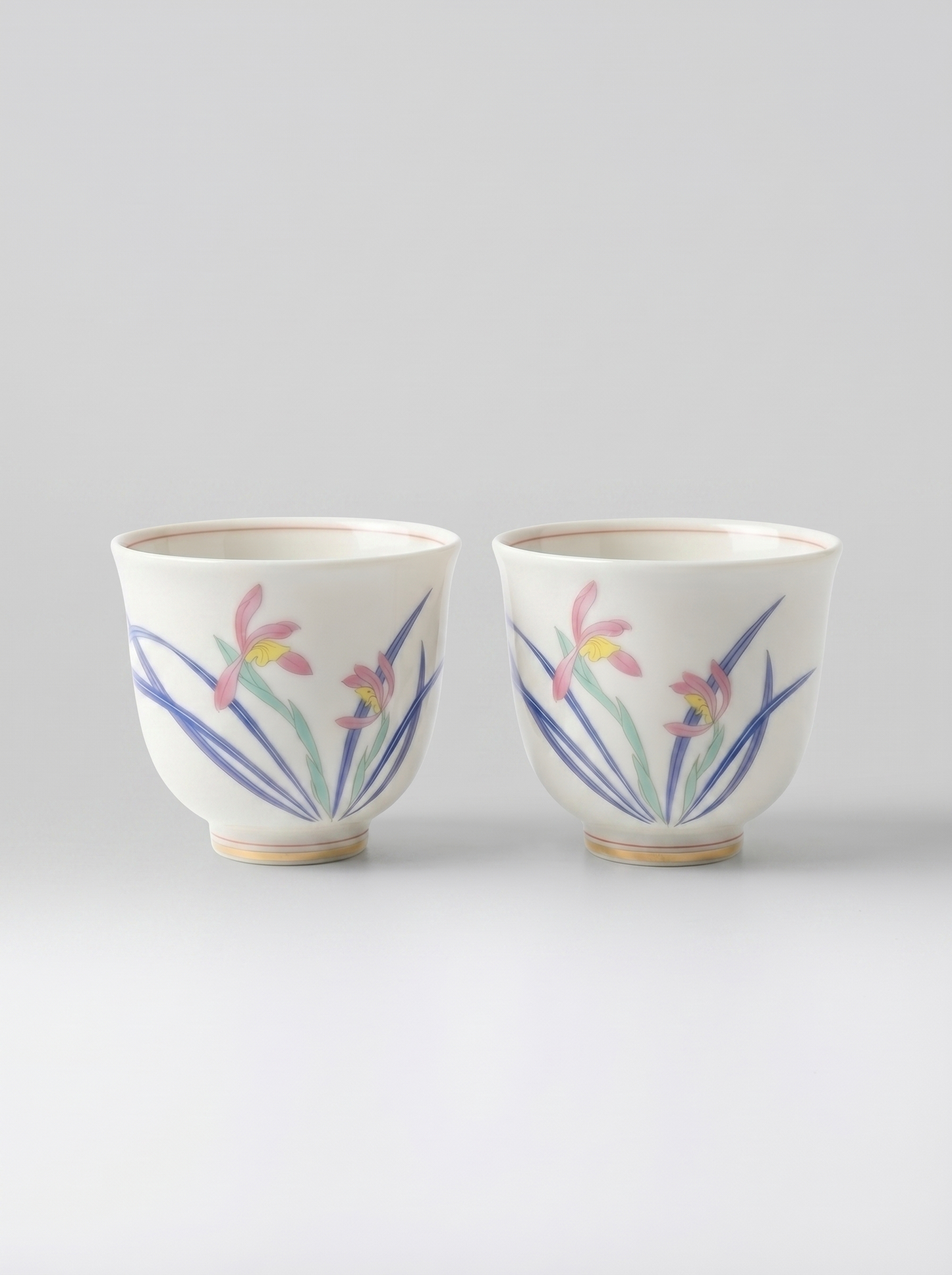 Two Japanese koransha porcelain teacups with floral designs on a light gray background