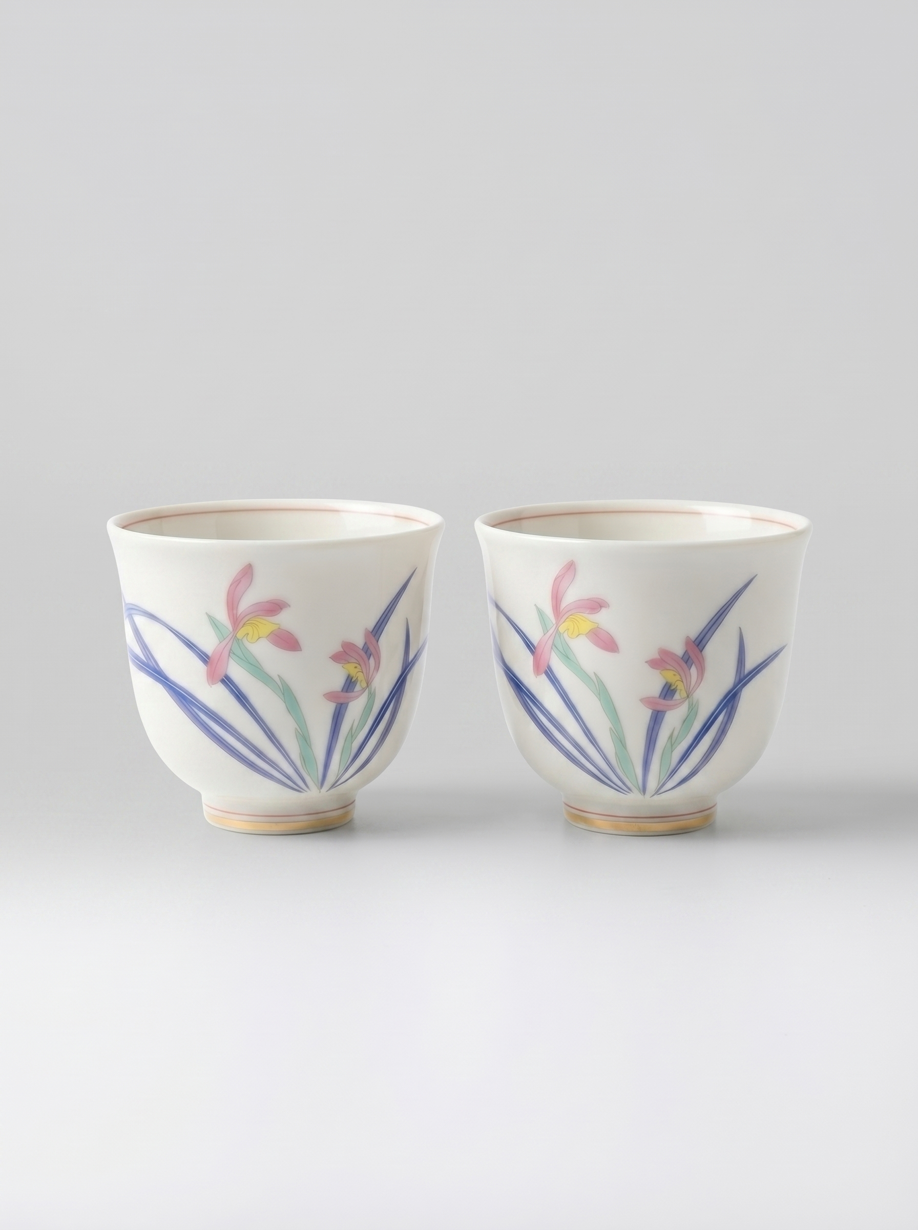 Two Japanese koransha porcelain teacups with floral designs on a light gray background