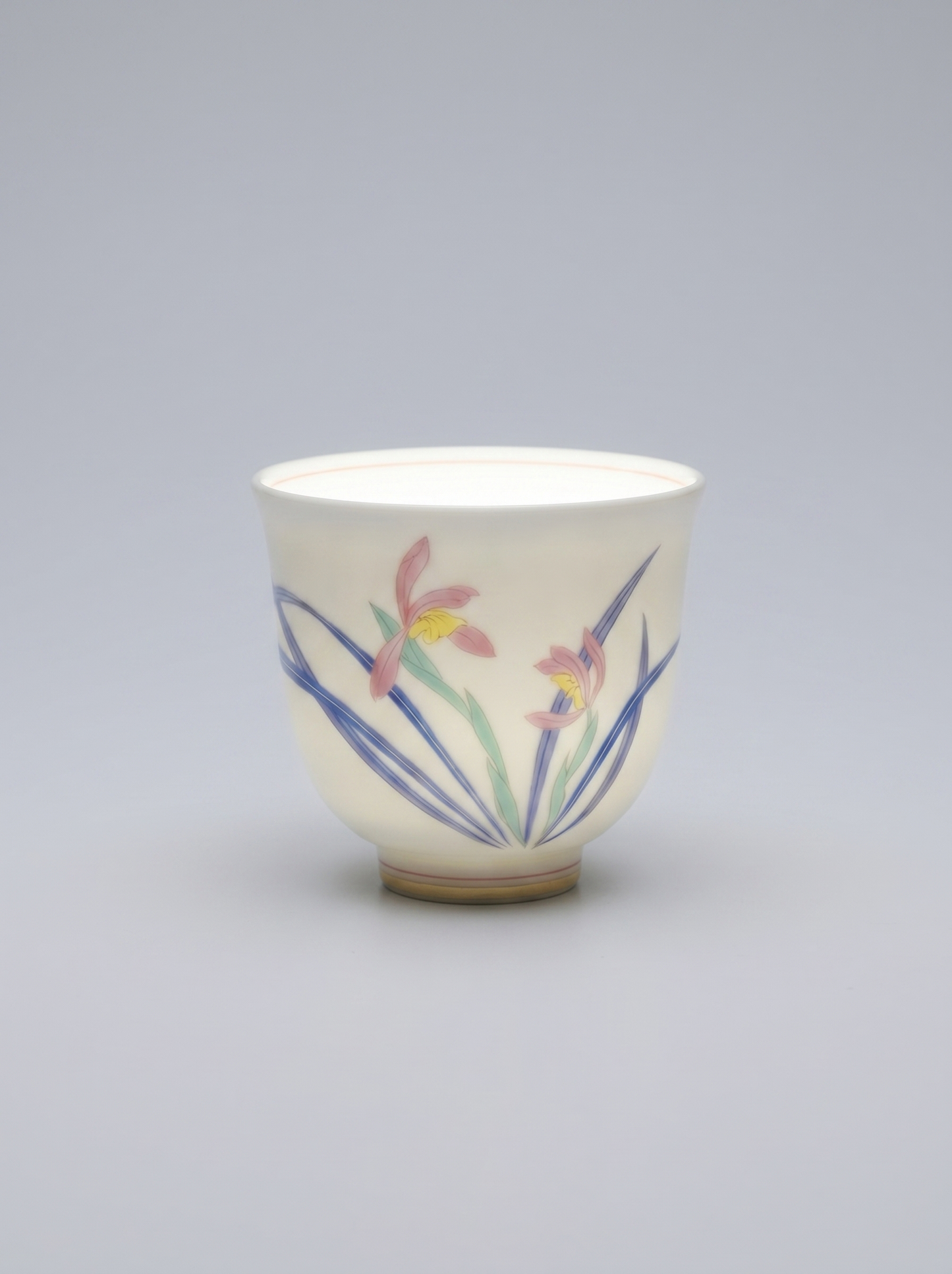 Japanese porcelain cup with a hand-painted wild orchid set against a neutral grey background, directional lighting highlights the thinness and translucency of the porcelain, casting soft shadows and emphasizing the delicate details of the artwork