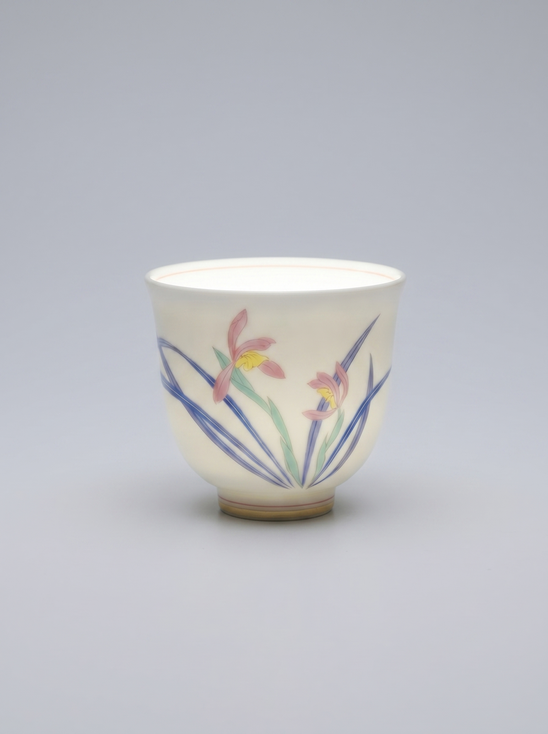 Japanese porcelain cup with a hand-painted wild orchid set against a neutral grey background, directional lighting highlights the thinness and translucency of the porcelain, casting soft shadows and emphasizing the delicate details of the artwork