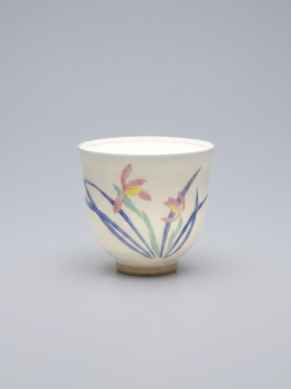 Japanese porcelain cup with a hand-painted wild orchid set against a neutral grey background, directional lighting highlights the thinness and translucency of the porcelain, casting soft shadows and emphasizing the delicate details of the artwork