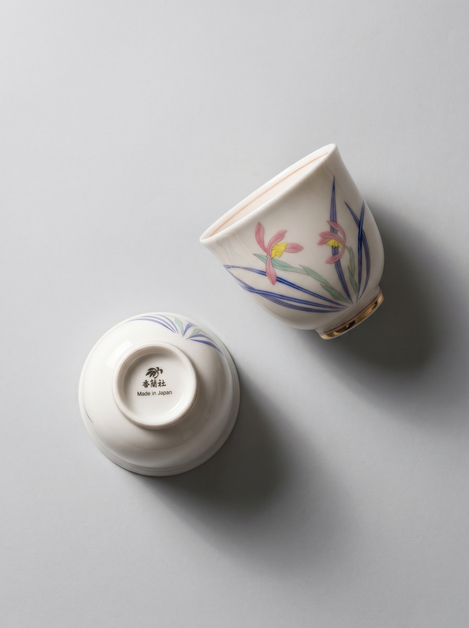 Two ceramic cups with floral designs on a light gray background