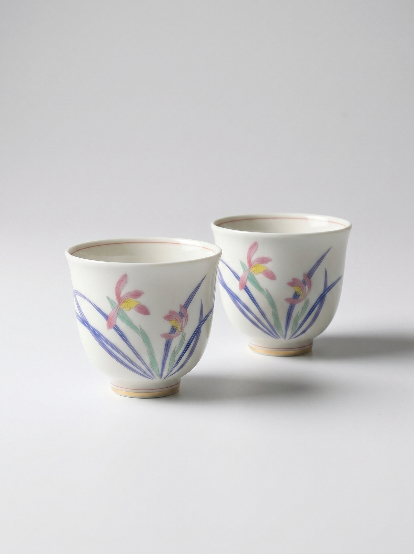 Two porcelain cups with wild orchid designs on a light gray background