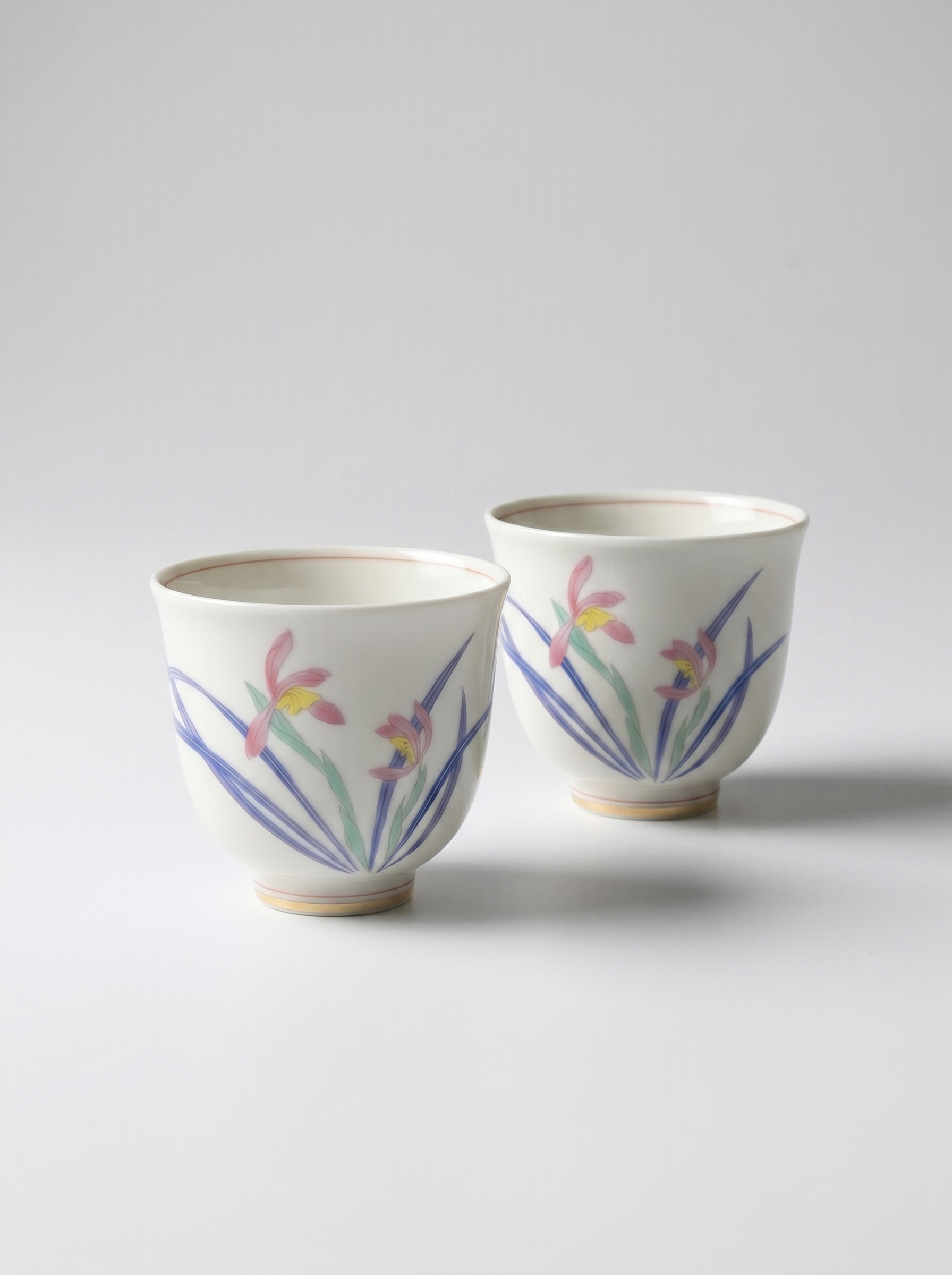 Two porcelain cups with wild orchid designs on a light gray background