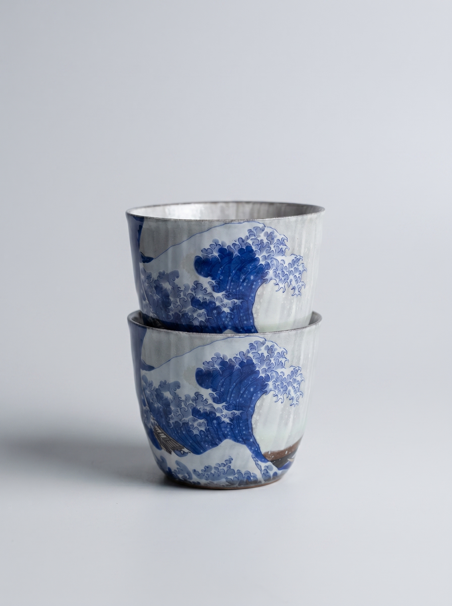 Two ceramic cups with blue wave design on a light gray background