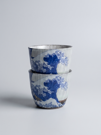 Two ceramic cups with blue wave design on a light gray background