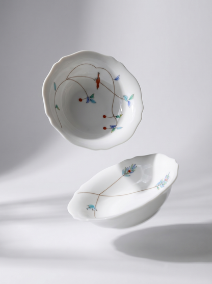 Two white japanese koransha porcelain bowls with floral patterns on a light gray background