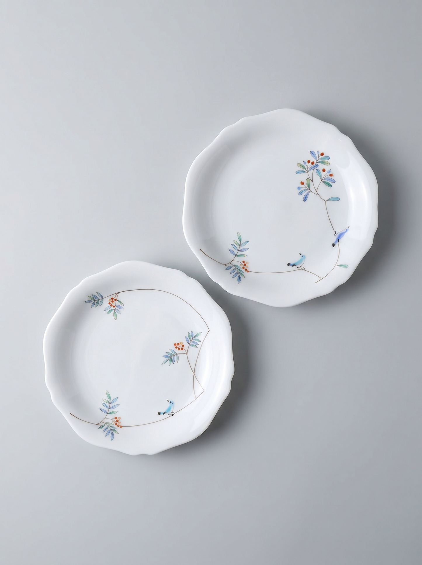 Two japanese porcelain dessert plates with floral patterns on a grey background
