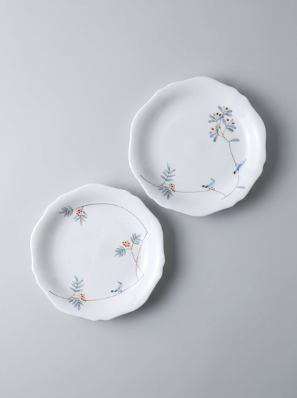 Two japanese porcelain dessert plates with floral patterns on a grey background