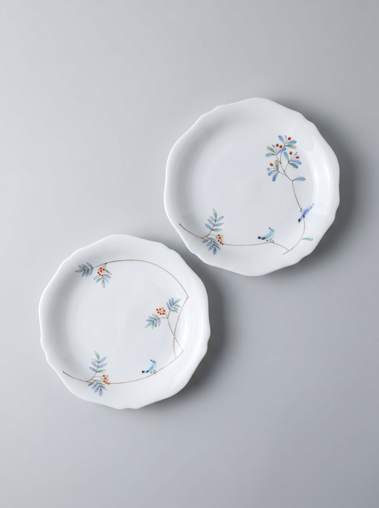 Two japanese porcelain dessert plates with floral patterns on a grey background