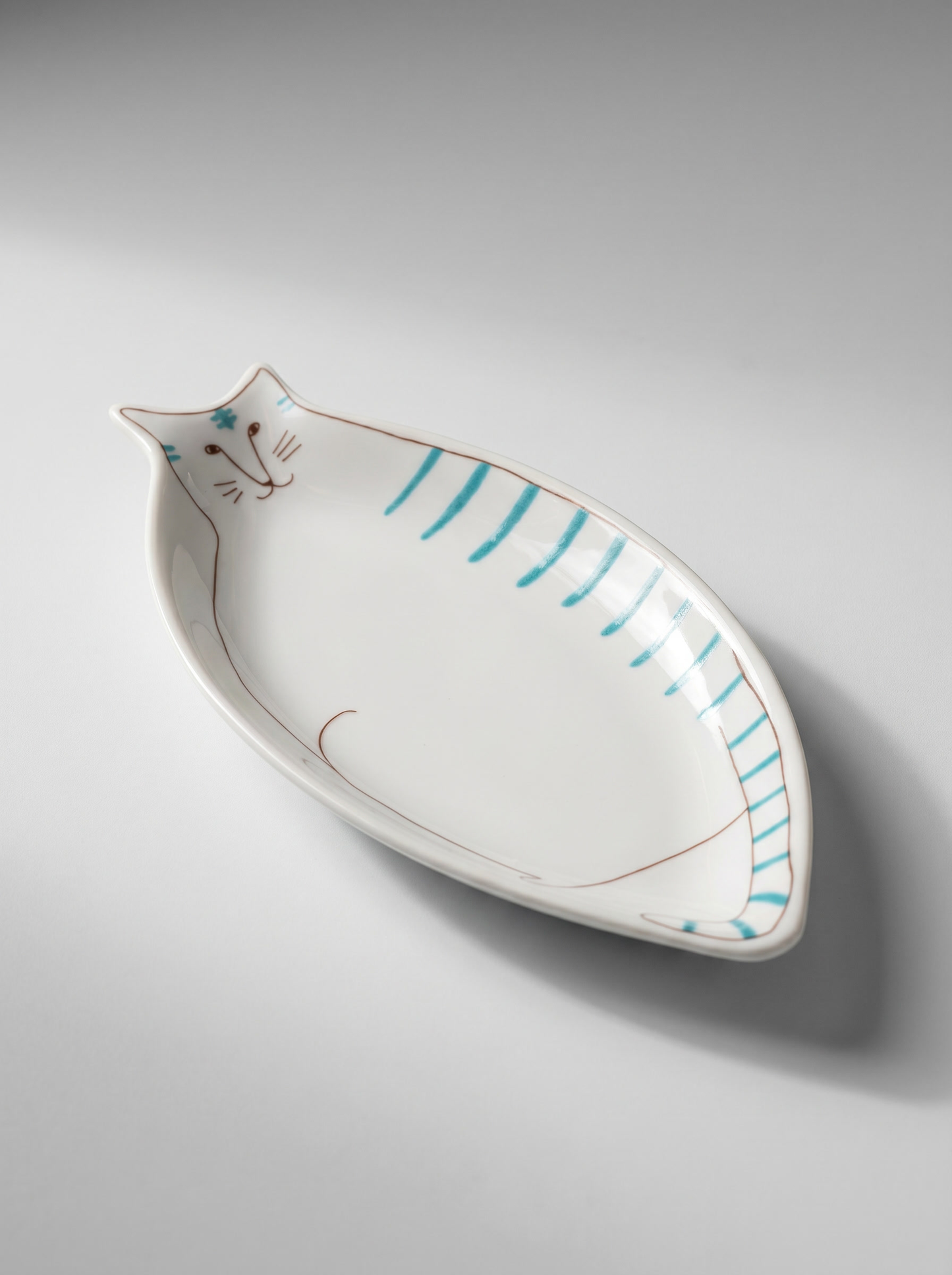 Cat-shaped ceramic plate with blue stripes on a gray background
