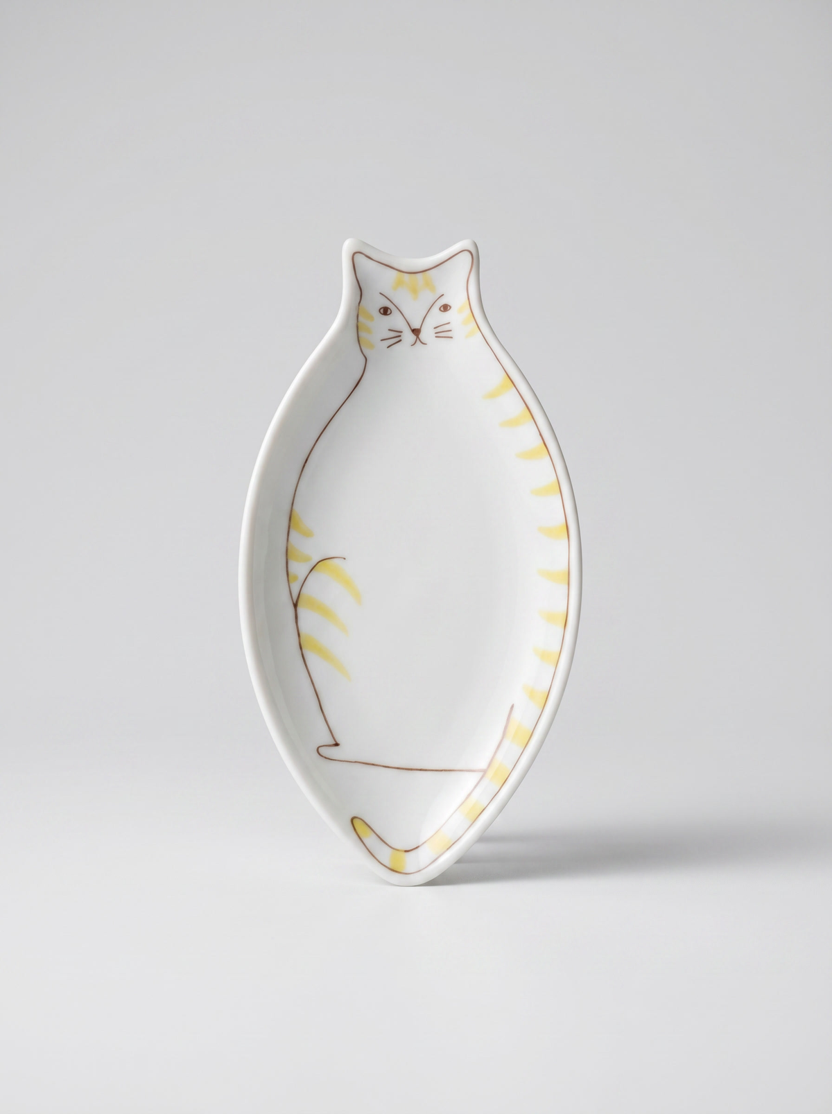 Cat-shaped ceramic plate with yellow accents on a light gray background
