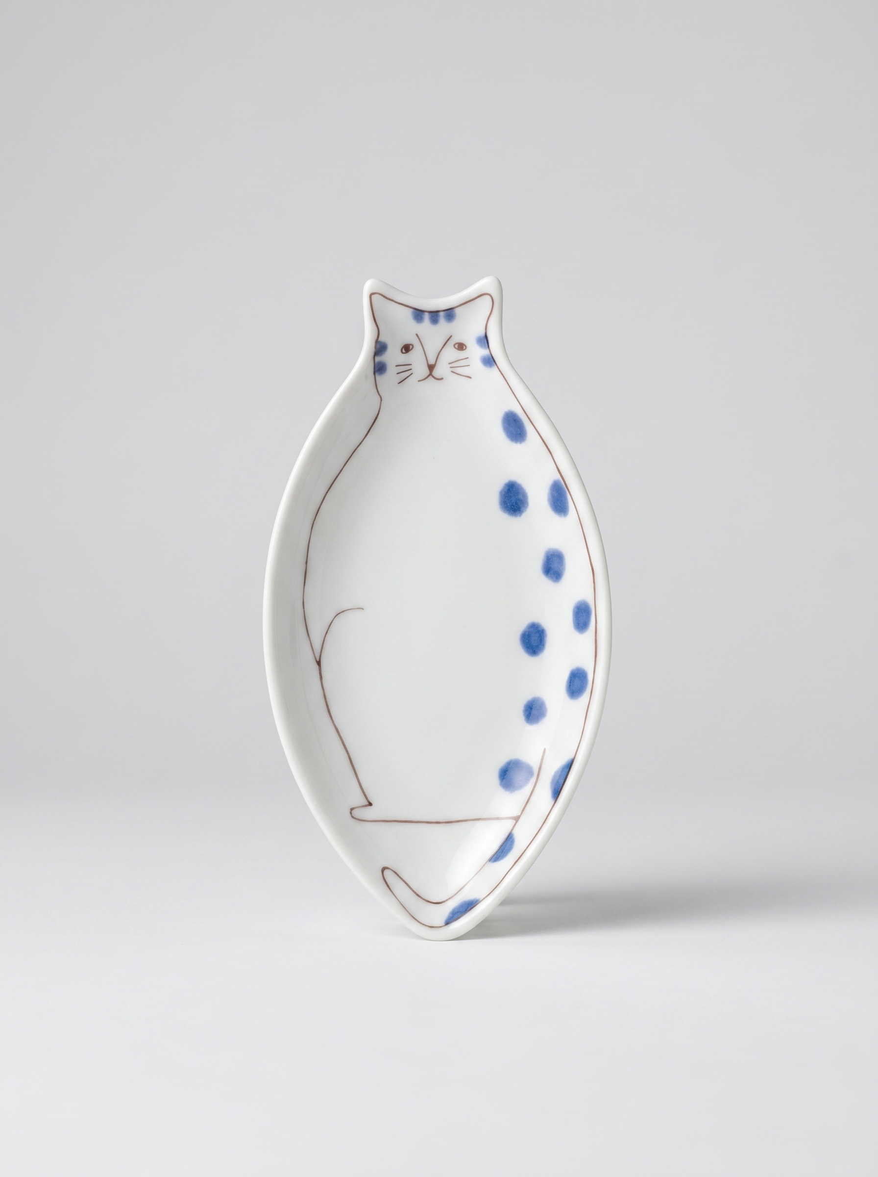 Japanese cat-shaped kutani ceramic sauce plate with blue polka dots on a light gray background
