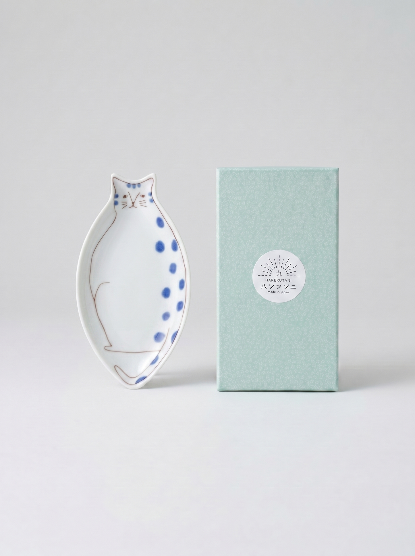 Cat-shaped ceramic dish with blue polka dots on a light gray background