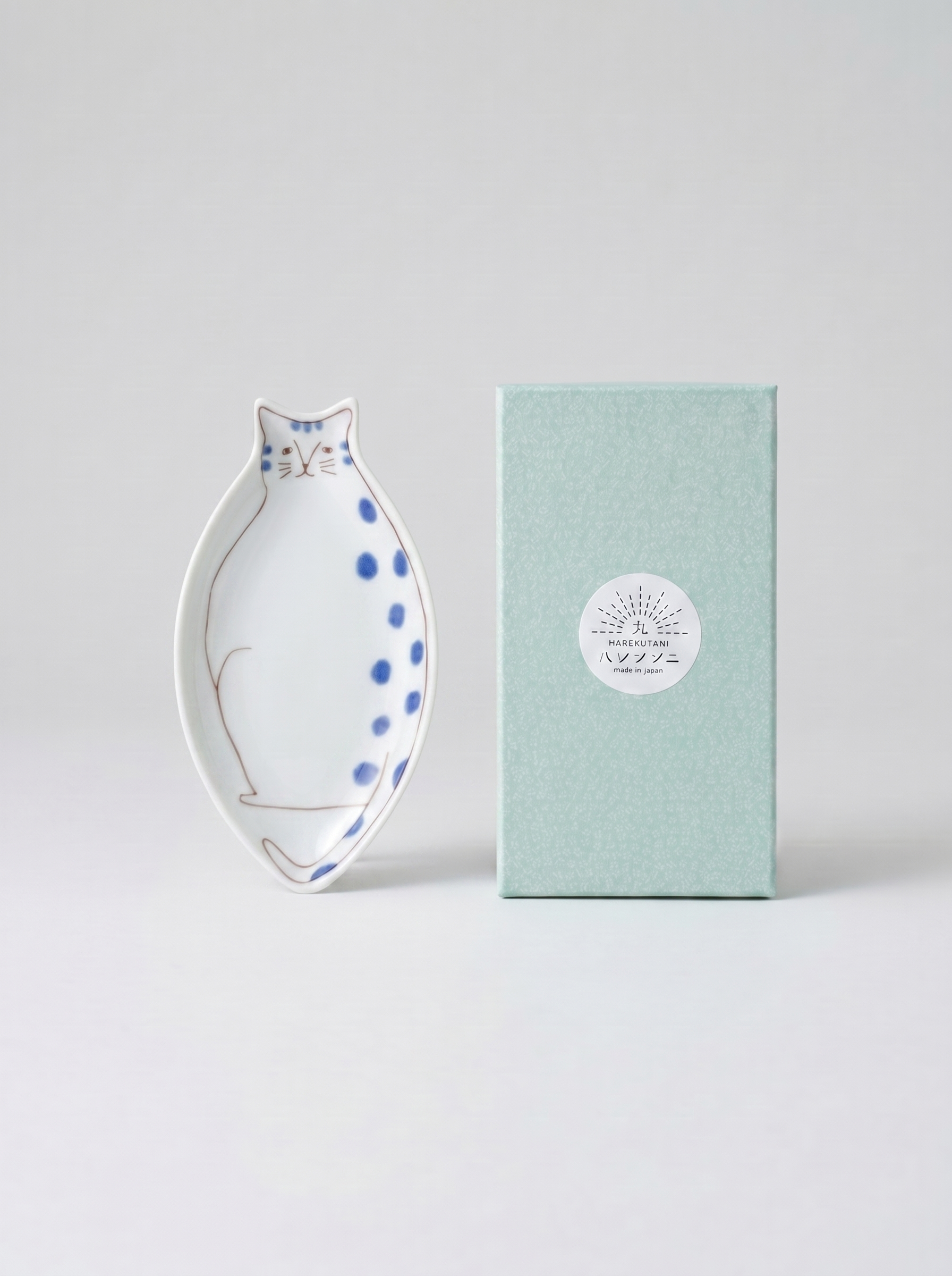 Cat-shaped ceramic dish with blue polka dots on a light gray background