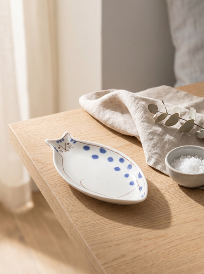 Ceramic cat-shaped dish with blue dots on a wooden surface with a white cloth and small bowl.