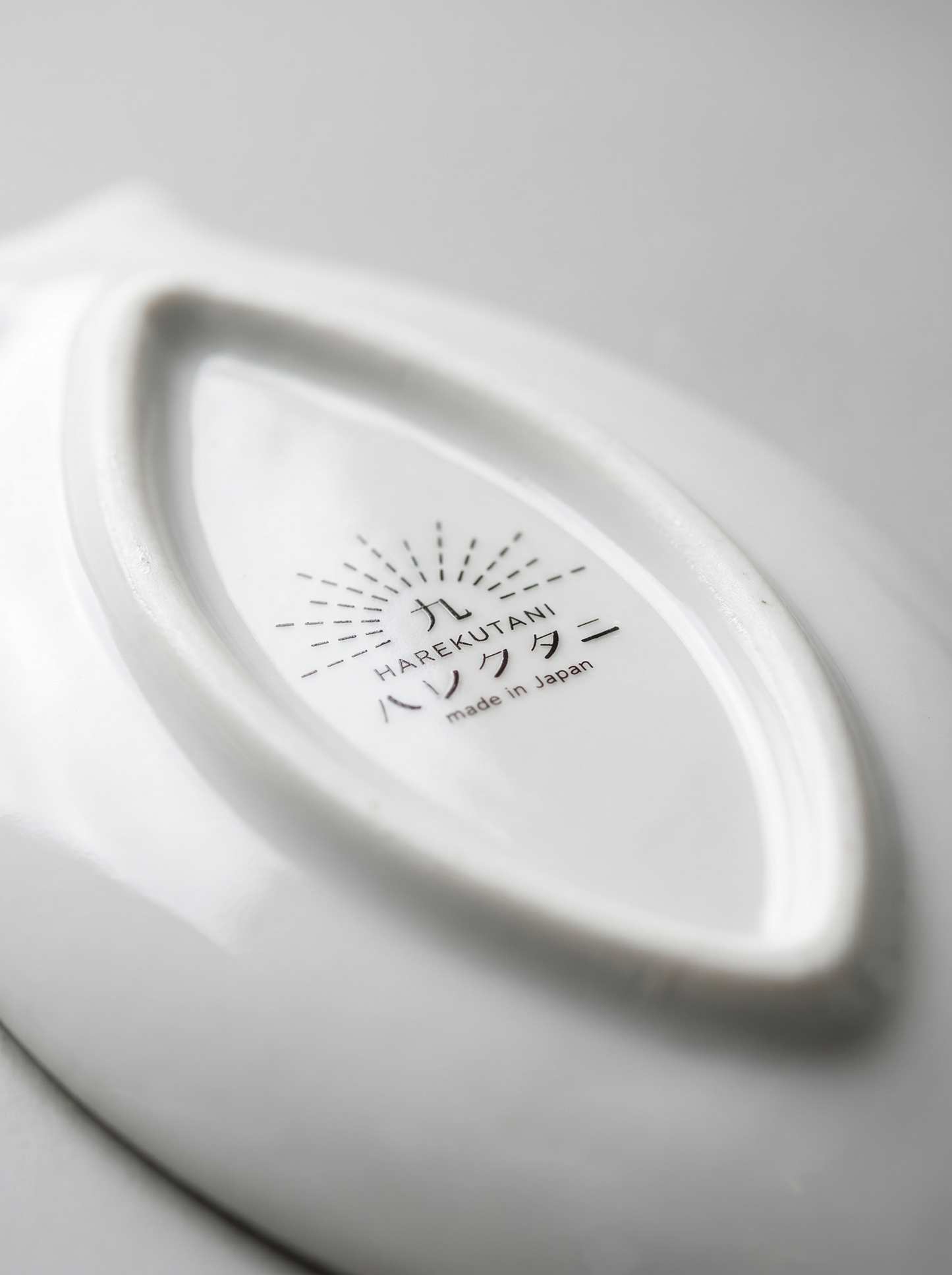 Close-up of a white ceramic product with 'Harekutani' branding on a light gray background