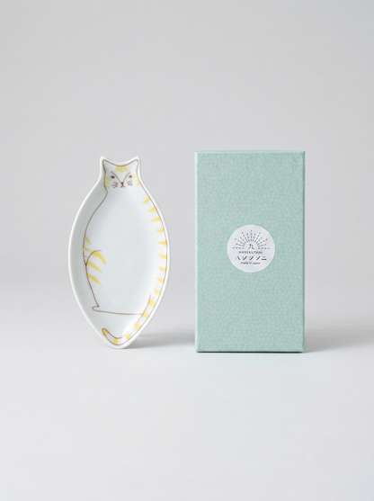 Decorative cat-shaped plate with yellow accents next to a green box on a light gray background