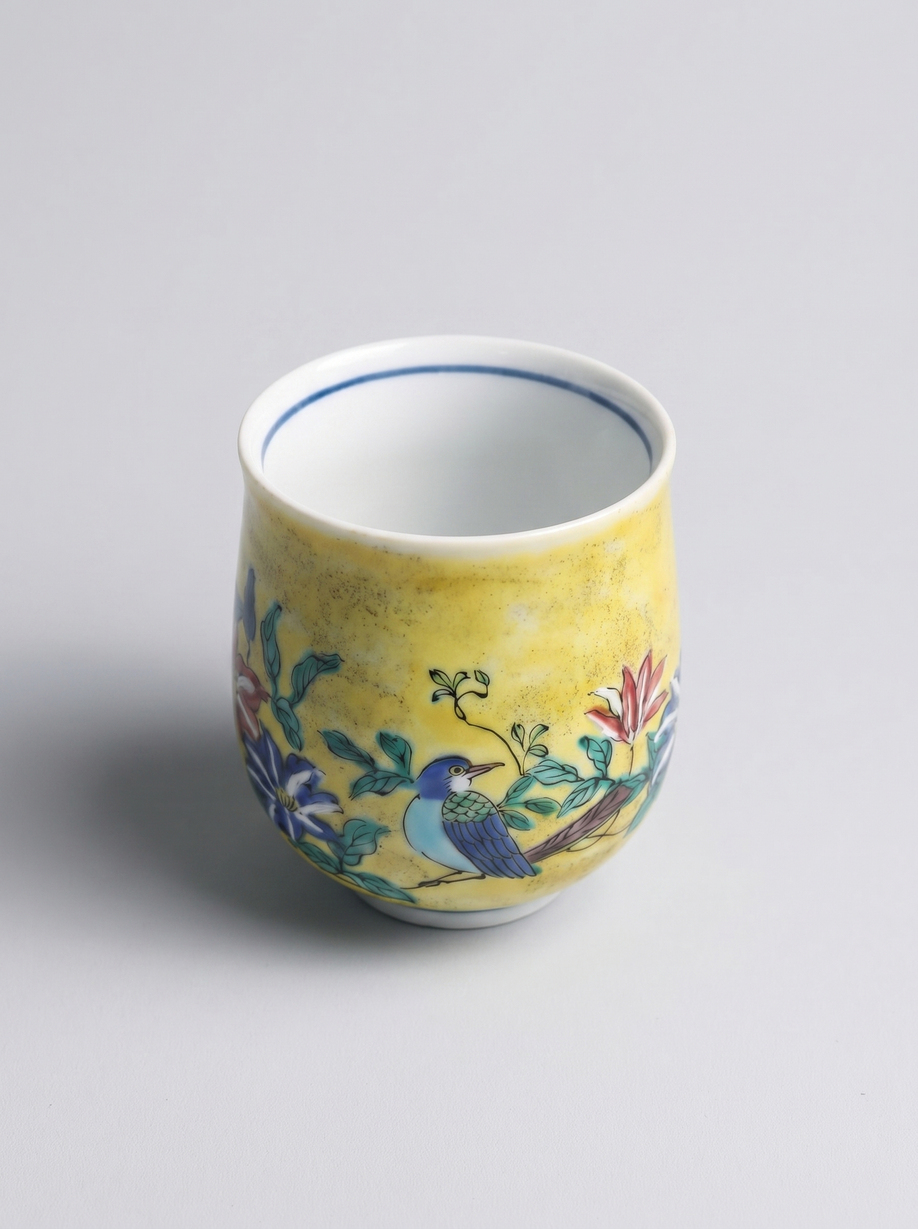 Ceramic cup with floral and bird design on a yellow background top view